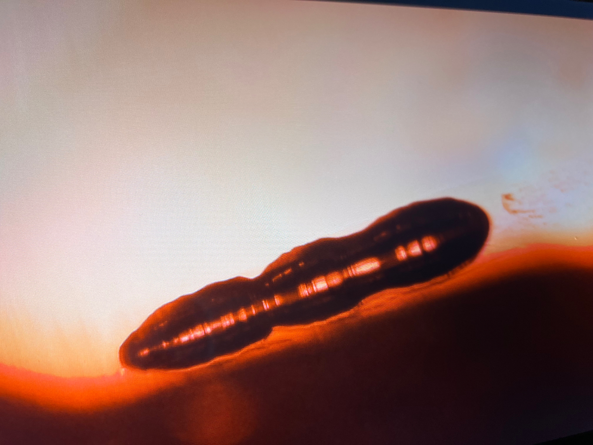 Microscopic view of an elongated tubular internal feature in a synthetic ruby under transmitted light